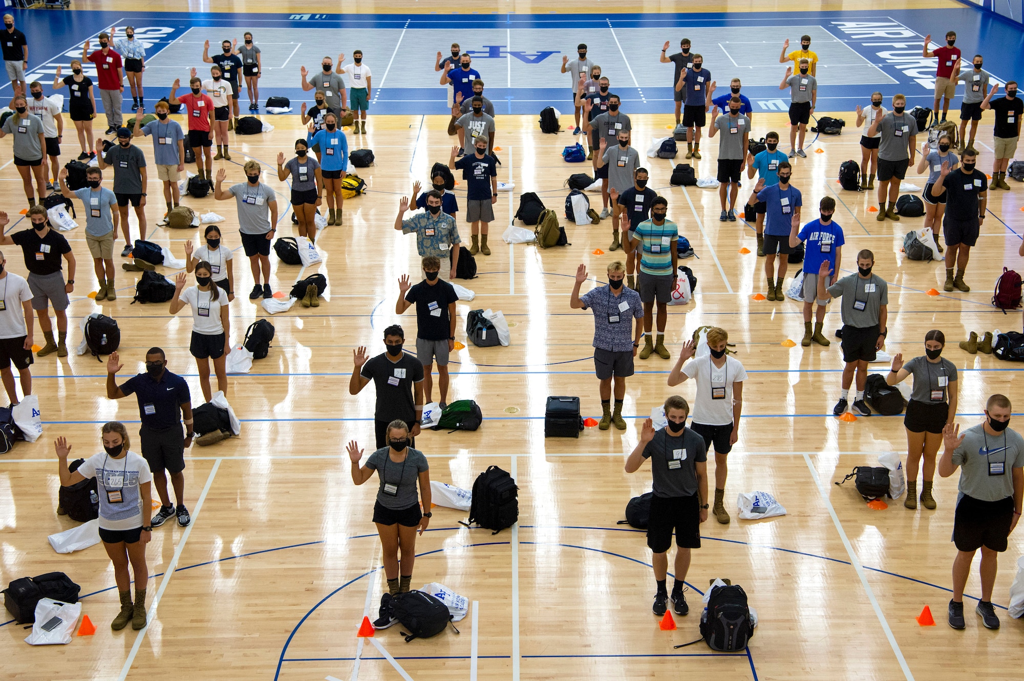 Basic cadets stand in a gymnasium to give their oath of enlistment.