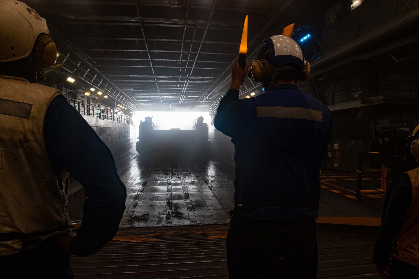 210618-N-XB010-1006 PHILIPPINE SEA (June 18, 2021) Seaman Garrett Jones, from Eagle River, Alaska, directs a landing craft air cushion as Ramp Marshall during its departure from the USS New Orleans (LPD 18) well deck during an exercise involving both Sailors and Marines. New Orleans, part of the America Amphibious Ready Group, along with the 31st Marine Expeditionary Unit, is operating in the U.S. 7th Fleet area of responsibility to enhance interoperability with allies and partners and serve as a ready response force to defend peace and stability in the Indo-Pacific region. (U.S. Navy photo by Mass Communication Specialist 2nd Class Desmond Parks)