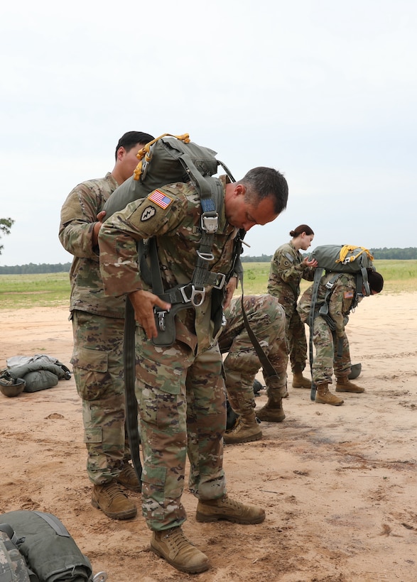 U.S. Army Reserve paratroopers with the U.S. Army Civil Affairs and Psychological Operations Command (Airborne) don their parachutes in preparation for nontactical airborne operations, June 5, 2021, at Saint Mere Eglise drop zone, Fort Bragg, N.C. USACAPOC(A) jumpmasters worked with Capt. Ignacio Rios, a Chilean jumpmaster assigned to the 1st Special Warfare Training Group(A), U.S. Army John F. Kennedy Special Warfare Center and School (USAJFKSWCS). Paratroopers jumping during the airborne operations were eligible to earn foreign wings.