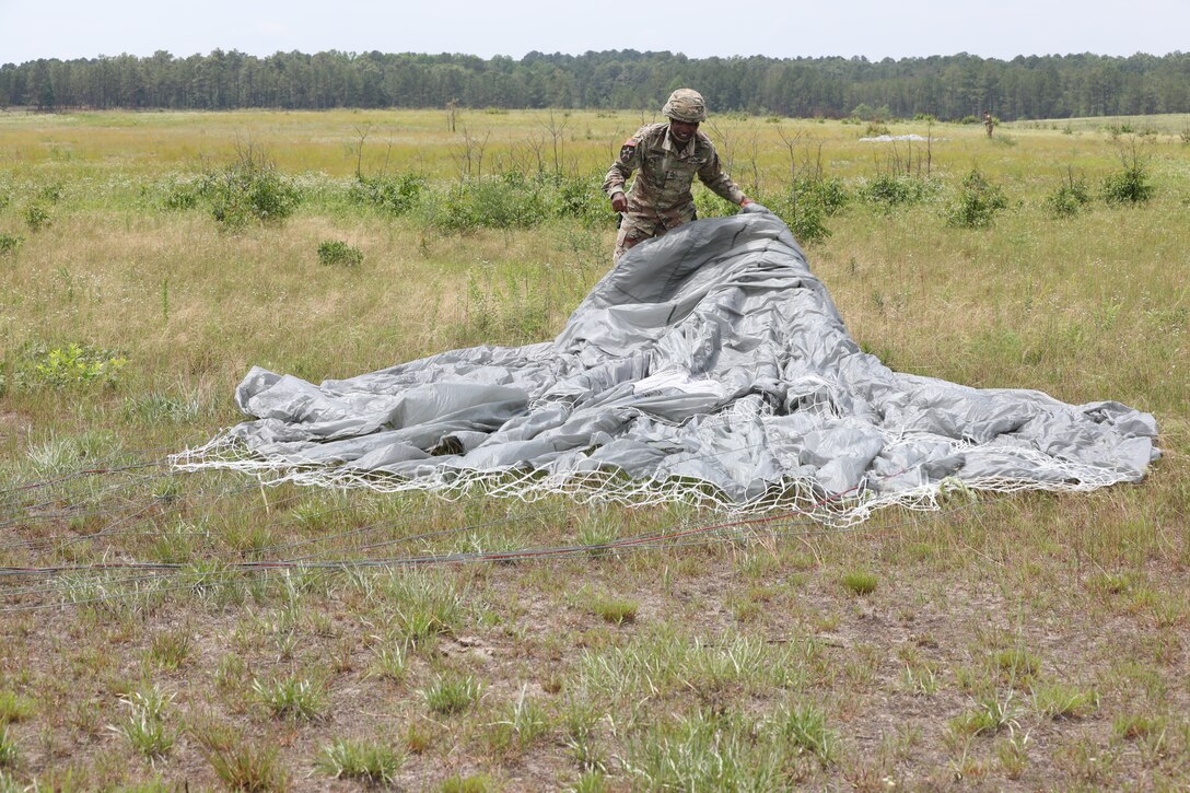 U.S. Army Reserve Master Sgt. Folarin L. Durosawo, assistant Inspector General for the U.S. Army Civil Affairs and Psychological Operations Command (Airborne), collects his parachute to bring back to a consolidated collection point during nontactical airborne operations at Saint Mere Eglise drop zone, Fort Bragg, N.C., June 5, 2021. USACAPOC(A) jumpmasters worked with Capt. Ignacio Rios, a Chilean jumpmaster assigned to the 1st Special Warfare Training Group(A), U.S. Army John F. Kennedy Special Warfare Center and School (USAJFKSWCS). Paratroopers jumping during the airborne operations were eligible to earn foreign wings.