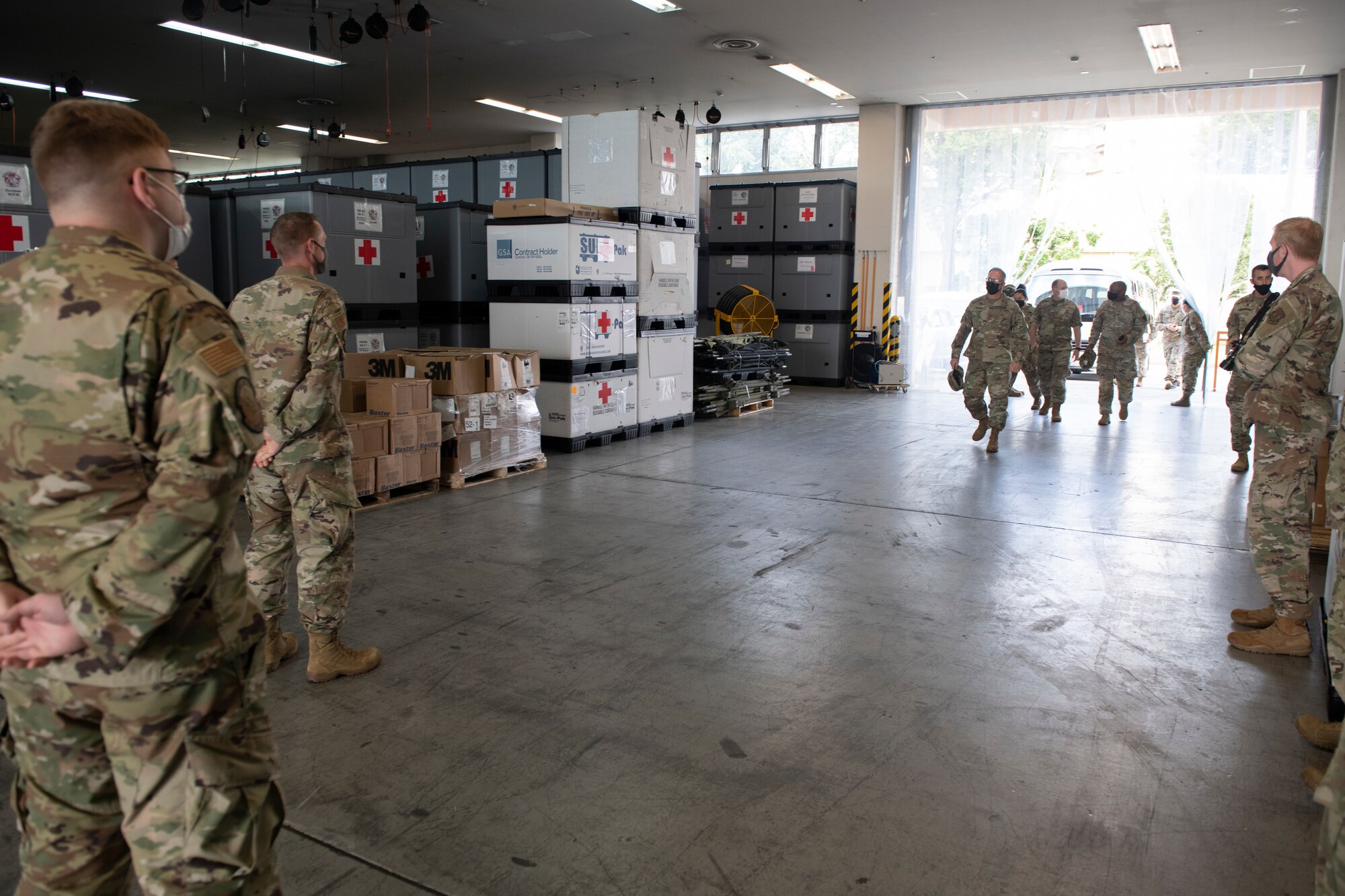Maj. Gen. Michael Place, 18th Medical Command (Deployment Support) commanding general, center, enters into the War Reserve Materiel warehouse at Yokota Air Base, Japan, June 24, 2021. During a tour of the base, Place visited both the WRM warehouse and Patient Movement Inventory Center to gain a better understanding of how Yokota Air Base could utilize its resources in a joint deployed environment. (U.S. Air Force photo by Staff Sgt. Joshua Edwards)