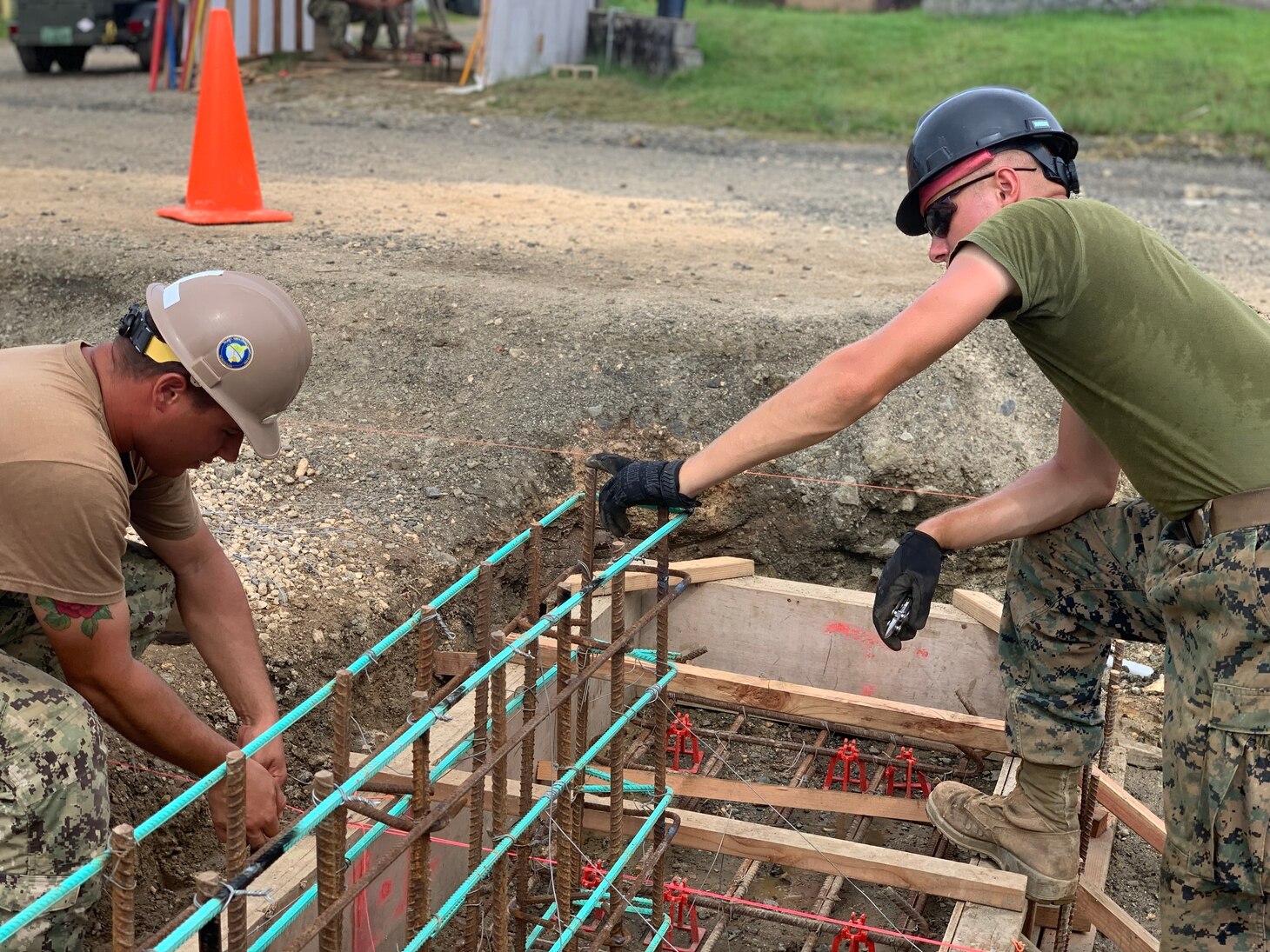 Builder 2nd Class Ryan Lamarre (left), assigned to Naval Mobile Construction Battalion (NMCB) FOUR, and Cpl. Seth Breitweser (right), assigned to the 7th Engineer Support Battalion (ESB), check a grade beam for quality control.