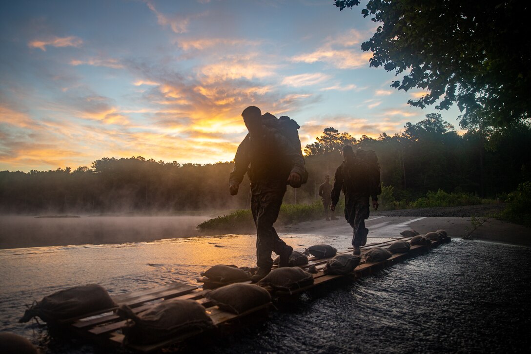 U.S. Marine Corps Capt. Thomas White, left, and Capt. Devon Sanderfield, both infantry officers with 2d Marine Division (MARDIV), cross a creek during a 20 km hike as part of the Division Leader Assessment Program (DLAP) at Fort Pickett, Va., June 24, 2021. DLAP assesses the preparedness of 2d MARDIV's newly-assigned infantry Captains by evaluating their mental, moral, and physical readiness for infantry company command, ensuring the Division places the right leaders in front of the right companies at the right time. DLAP is a key component in the Division's mission to train and certify units that demonstrate apex levels of lethality, endurance and comprehensive warfighting ability to be employed by their gaining higher headquarters immediately upon deployment. (U.S. Marine Corps photo by Lance Cpl. Brian Bolin Jr.)