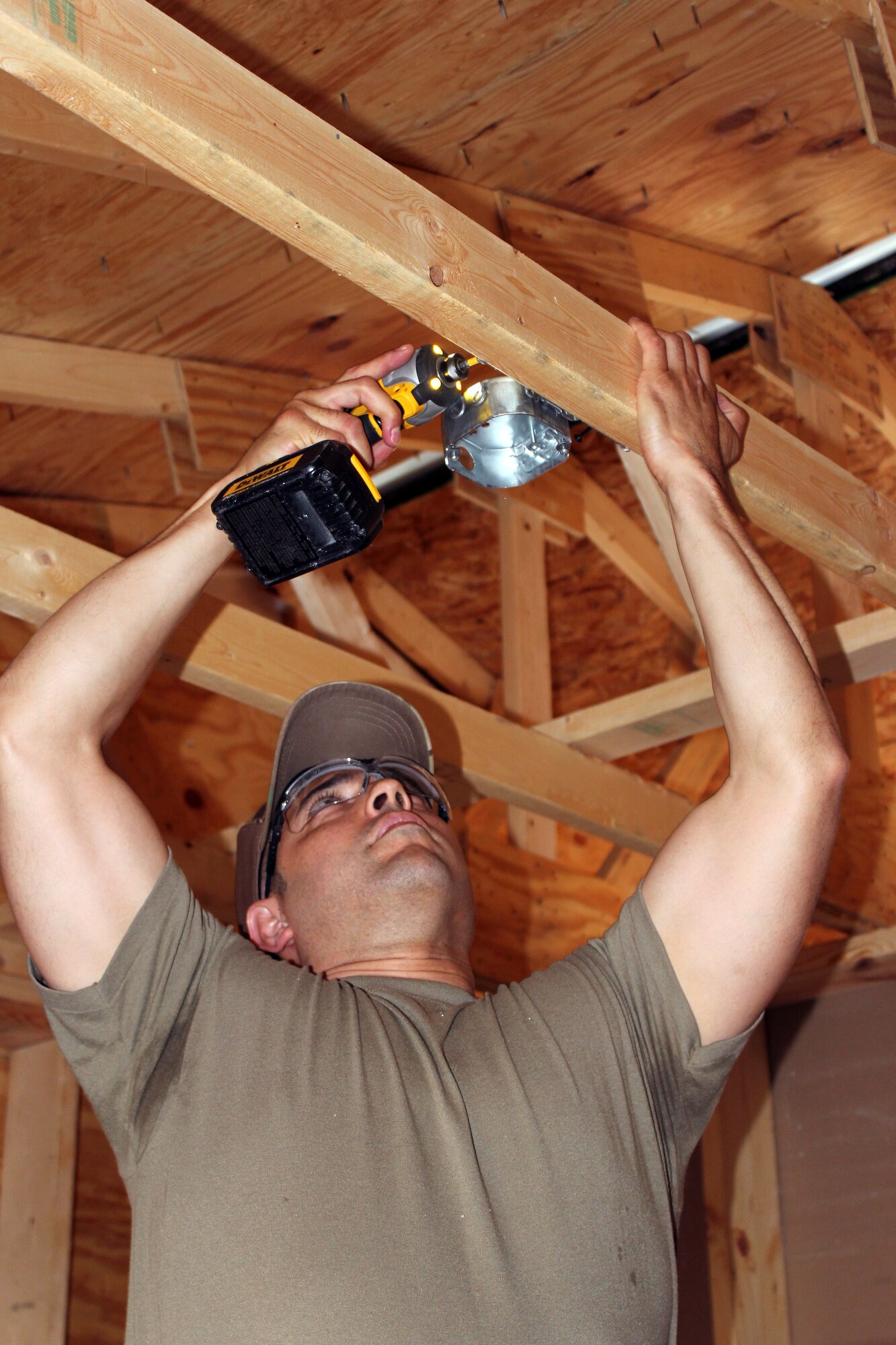 Tech. Sgt. Javier Garcia installs a light fixture in a temporary building at at Selfridge Air National Guard Base, Mich., June 6, 2021. The 127th Civil Engineer Squadron built the building to be able to conduct hands-on building trades training.