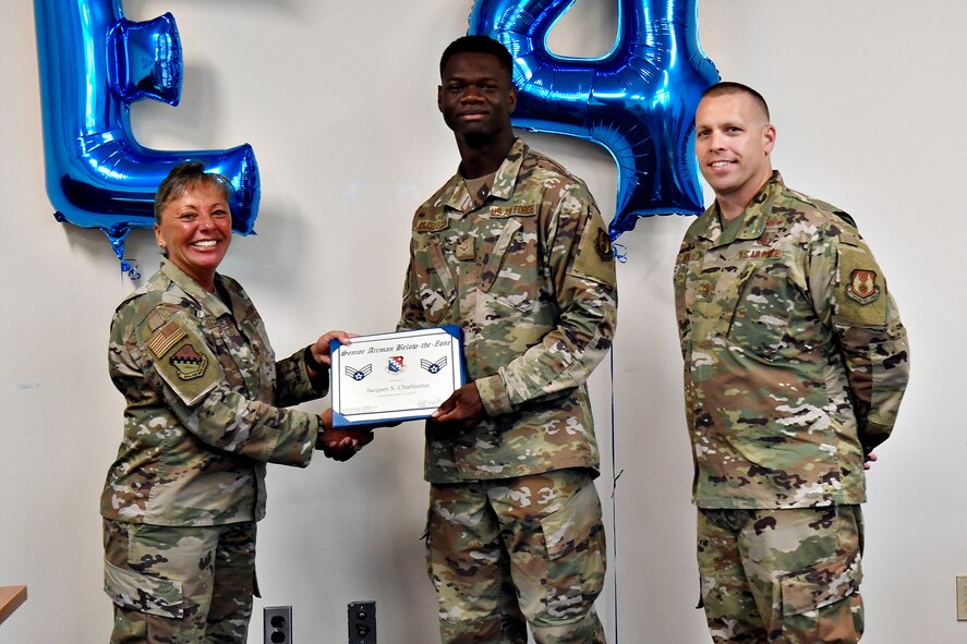 Col. Katrina Stephens, installation commander, and Chief Master Sgt. William Hebb, installation command chief, present Airman 1st Class Jacques Charleceus, 66th Comptroller Squadron financial management specialist, with a promotion to senior Airman, below the zone, at Hanscom Air Force Base, Mass., June 25. Below the Zone is a competitive early promotion that recognizes top performers. (U.S. Air Force photo by Linda LaBonte Britt)