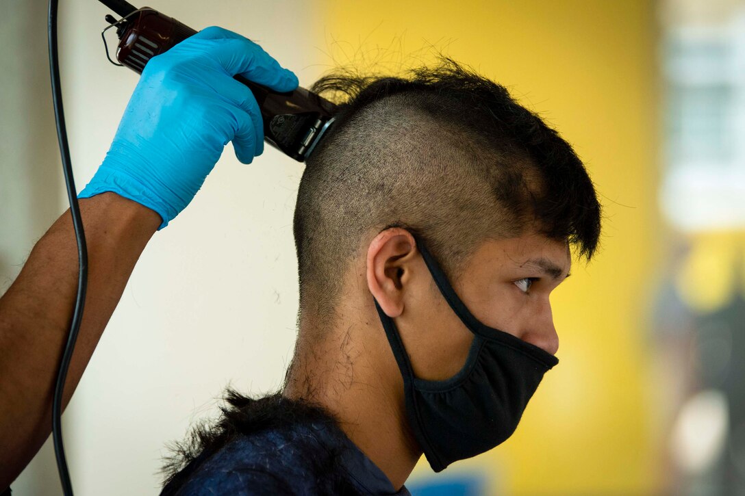 A cadet wearing face mask receives a haircut.