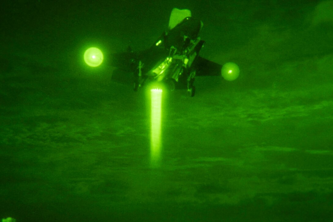 An aircraft prepares to land illuminated by green light.