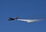 About 150 feet above a tree line, a California Air National Guard C-130 aircraft releases 3,000 gallons of water, covering nearly a quarter mile, during aerial wild land firefighting training June 15-19, 2020, at the Tahoe National Forest.