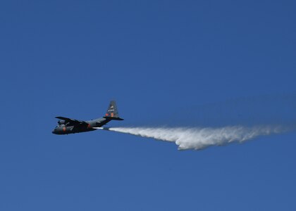 About 150 feet above a tree line, a California Air National Guard C-130 aircraft releases 3,000 gallons of water, covering nearly a quarter mile, during aerial wild land firefighting training June 15-19, 2020, at the Tahoe National Forest.