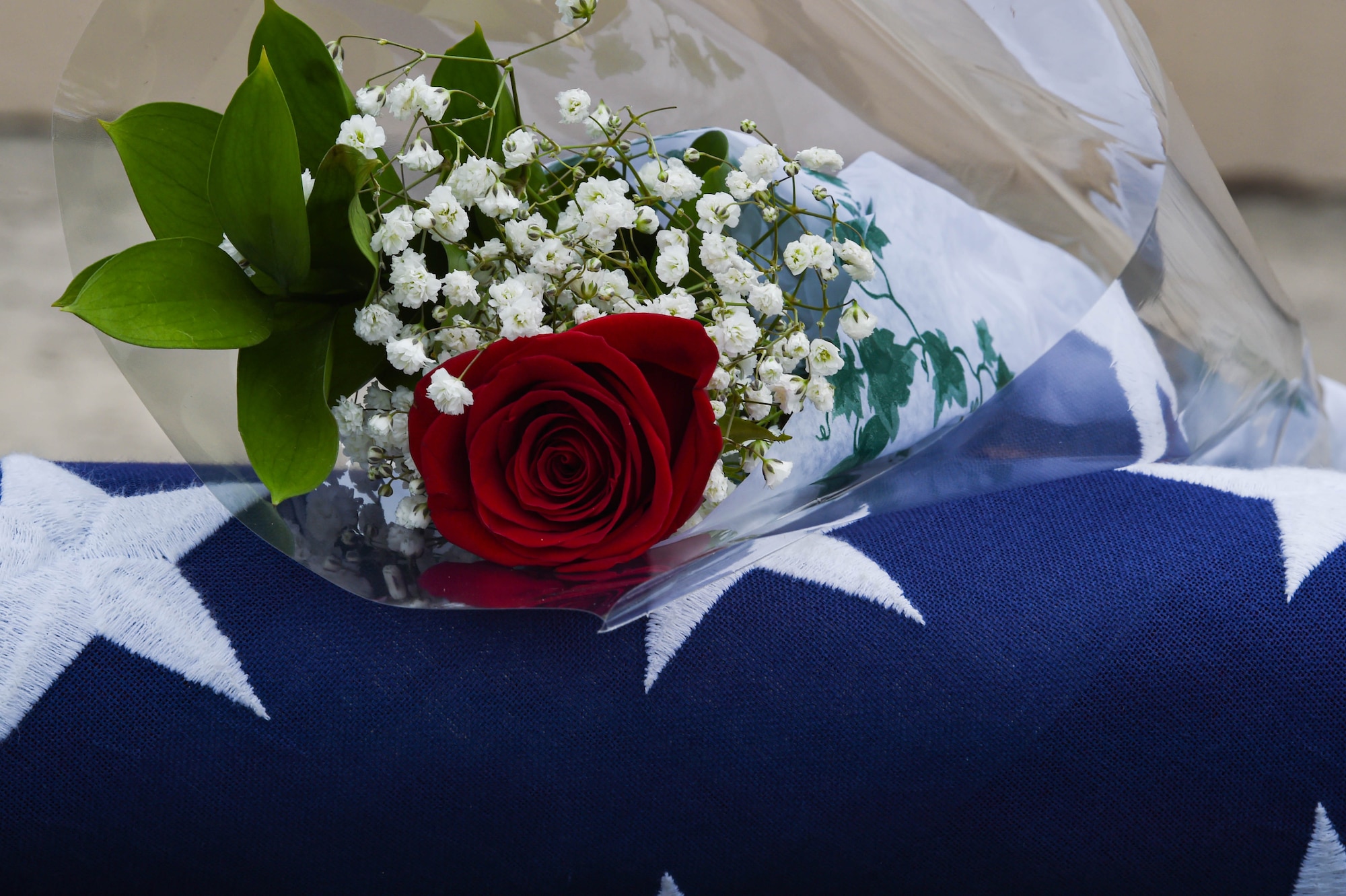 A rose and flag sit on an empty seat during a memorial ceremony