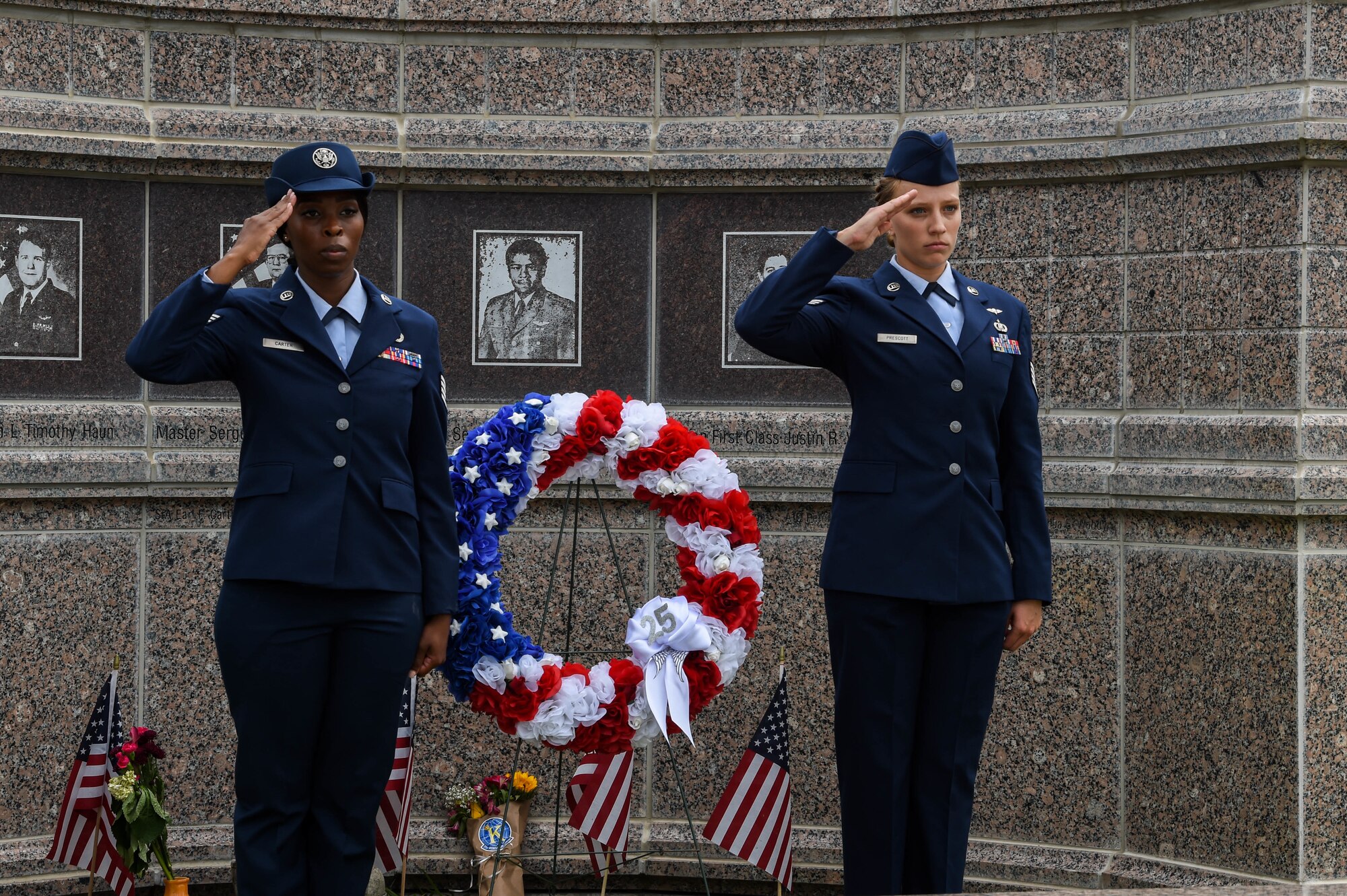 Two Airmen salute during a wreath-laying