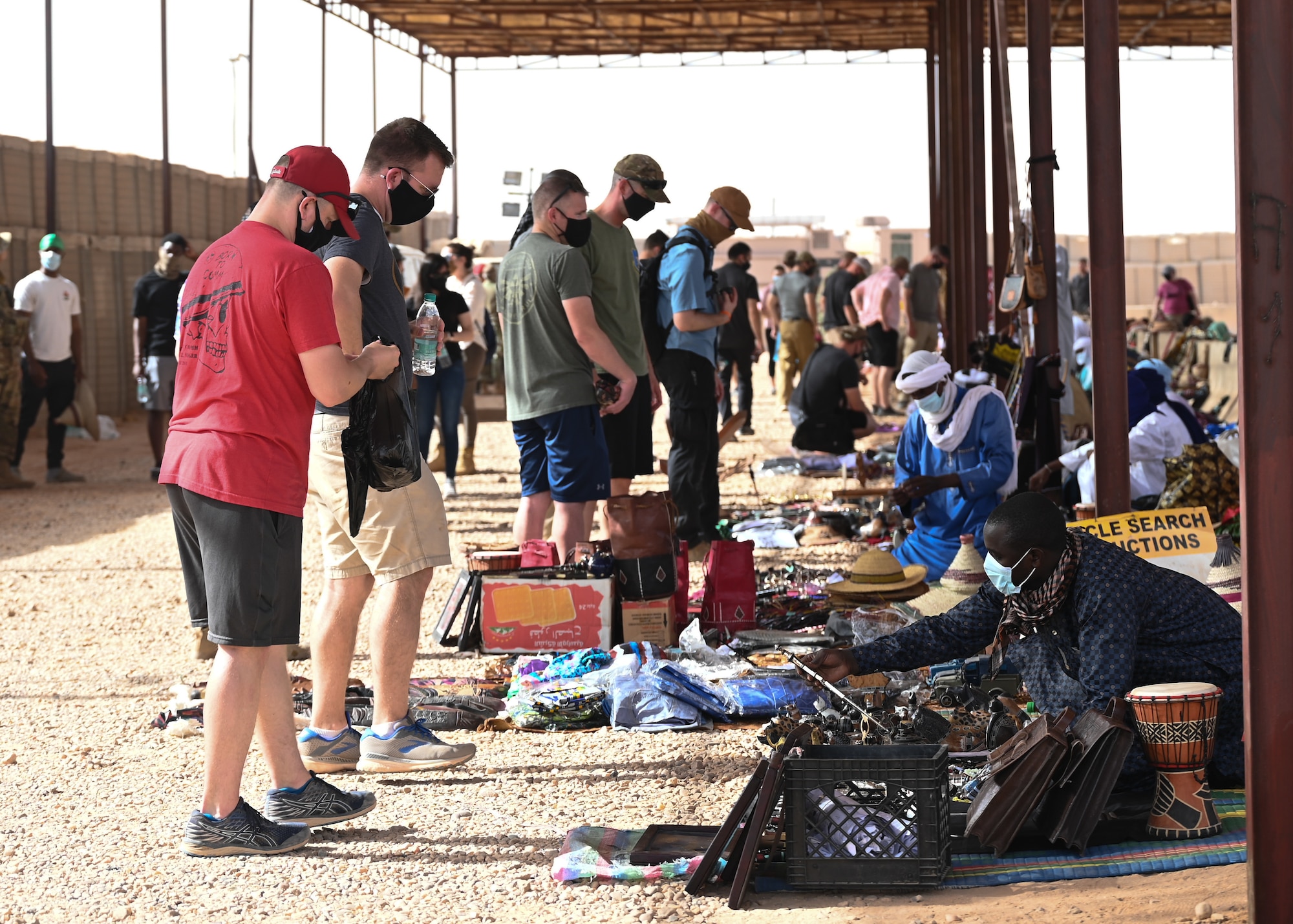 U.S. service members assigned to Nigerien Air Base 201 browse through vendors during a bazaar at the base in Agadez, Niger, June 20, 2021. The bazaar had a wide range of items, to include handmade art, traditional Nigerien clothing, daggers and jewelry that attendees were able to purchase from the local vendors.  The top three items were jewelry, figurines and clothing. (U.S. Air Force photo by Airman 1st Class Jan K. Valle)