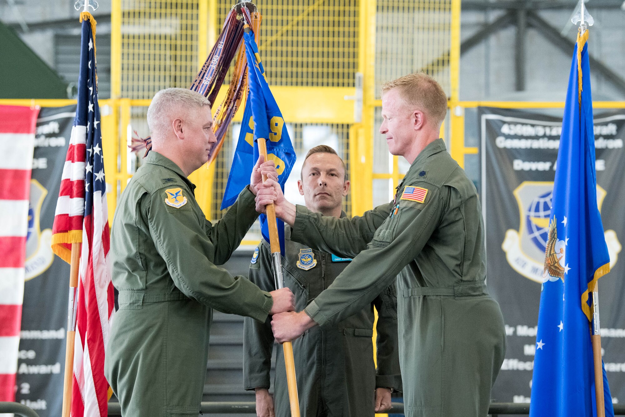 Lt. Col. John Habbestad, right, outgoing 9th Airlift Squadron commander, passes the guidon to Col. Mike Peeler, 436th Operations Group commander, during a change of command ceremony at Dover Air Force Base, Delaware, June 25, 2021. The ceremony saw Habbestad relinquish command to Lt. Col. James Shepard. The 9th AS routinely trains to provide global reach with unique outsized and oversized airlift capability on the C-5M Super Galaxy. (U.S. Air Force photo by Mauricio Campino)