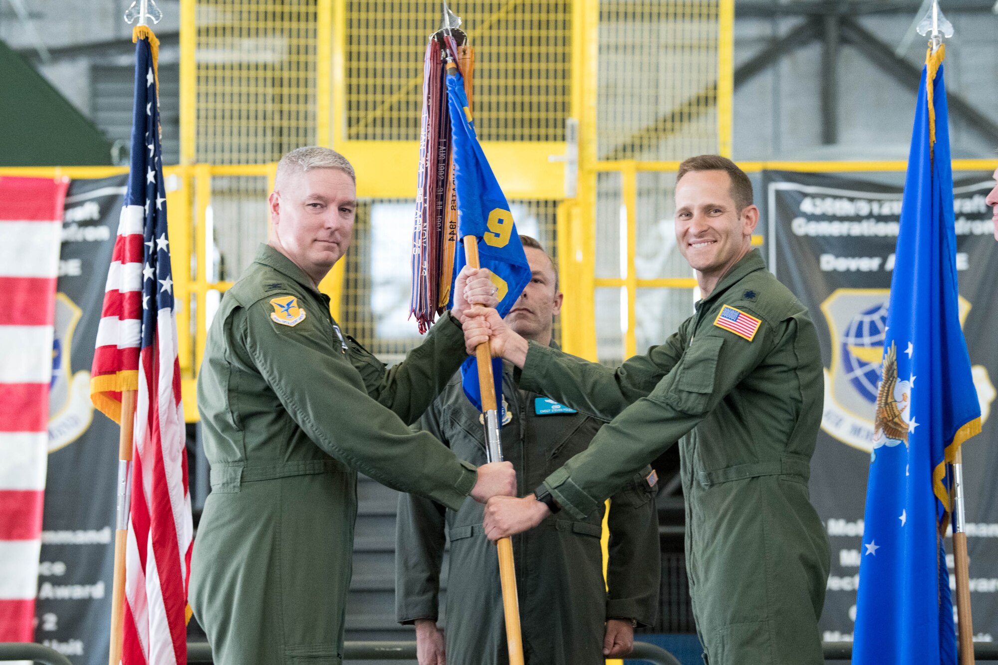 Col. Mike Peeler, left, 436th Operations Group commander passes the guidon to Lt. Col. James Shepard, incoming 9th Airlift Squadron commander, during a change of command ceremony at Dover Air Force Base, Delaware, June 25, 2021. The ceremony saw Lt. Col. John Habbestad relinquish command to Shepard. The 9th AS routinely trains to provide global reach with unique outsized and oversized airlift capability on the C-5M Super Galaxy. (U.S. Air Force photo by Mauricio Campino)