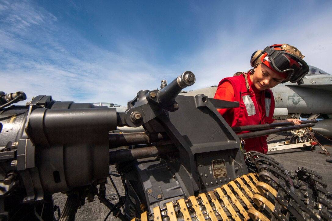 An airman attaches a gun barrel to a gatling gun.