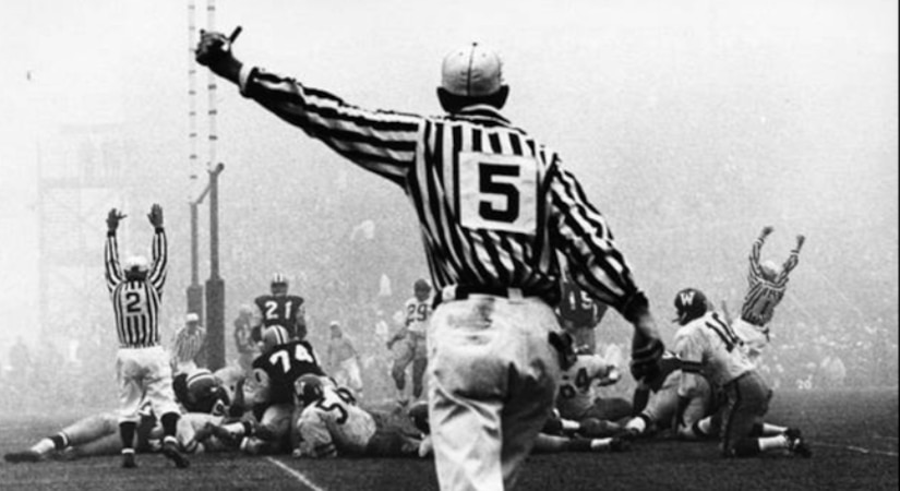 A team makes touchdown as a referee moves toward the action on a foggy field.