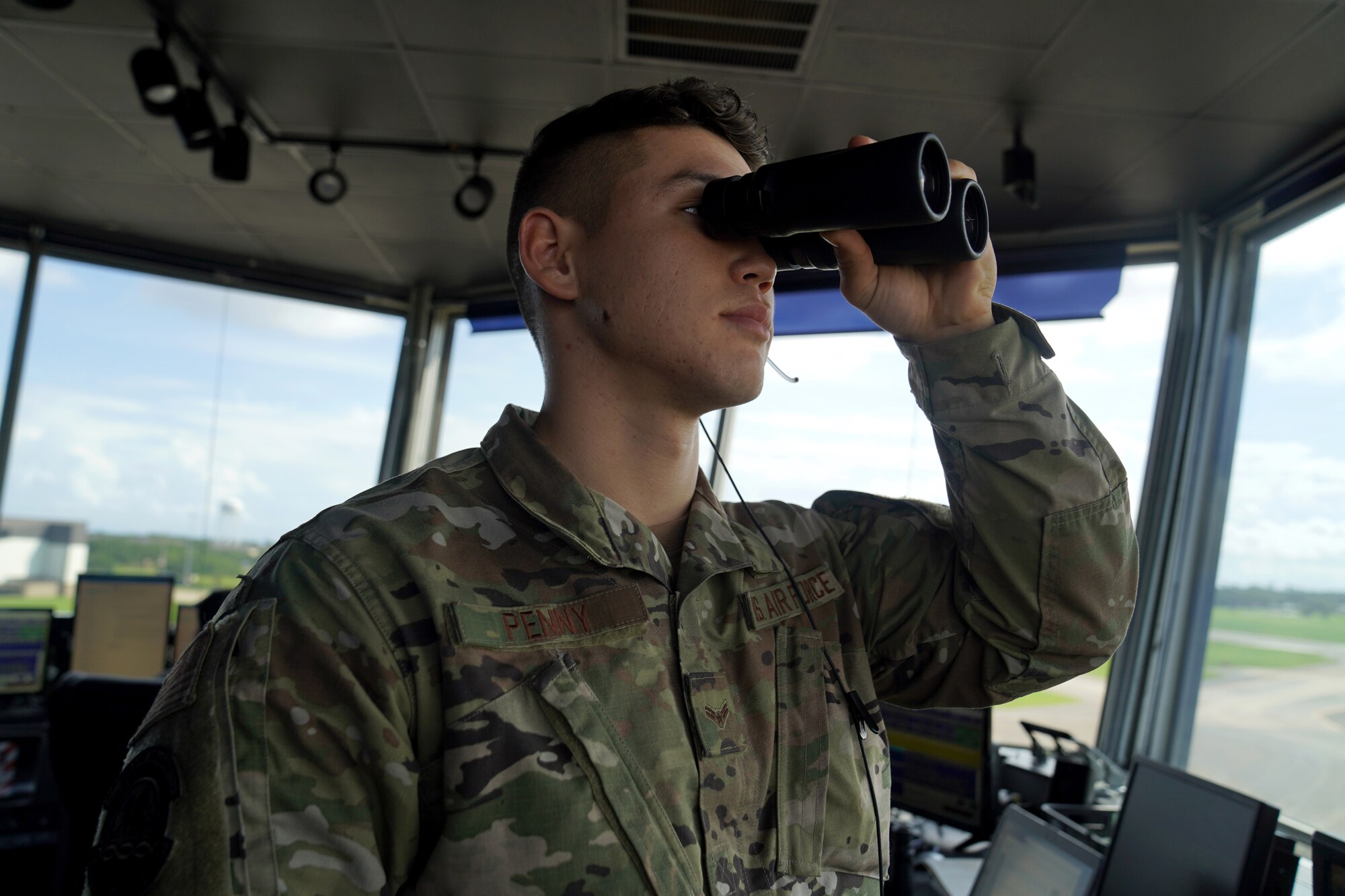 U.S. Air Force Airman 1st Class Jacob Penny, 81st Training Wing air traffic controller, poses for a photo with binoculars inside the Keesler Air Traffic Control tower at Keesler Air Force Base, Mississippi, June 25, 2021. The 81st TRW Operations Support Flight traffics the aircraft on the Keesler flightline and the local airspace. (U.S. Air Force photo by Senior Airman Seth Haddix)