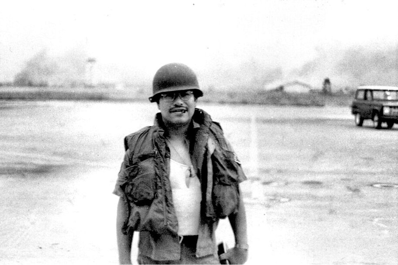 A man wearing a military helmet stands on a field.