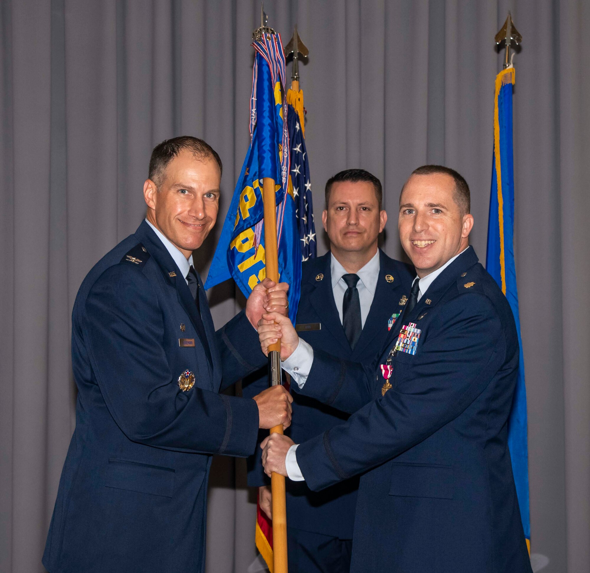 Maj. Kevin Byram, right, outgoing 436th Comptroller Squadron commander, passes the guidon to Col. Matt Husemann, left, 436th Airlift Wing commander, during a change of command ceremony on Dover Air Force Base, Delaware, June 28, 2021. The ceremony saw Byram relinquish command to Lt. Col. Gretchen Lewis. (U.S. Air Force photo by Airman 1st Class Stephani Barge)