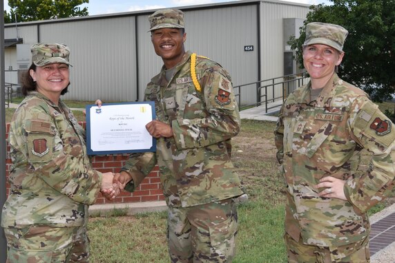 U.S. Air Force Col. Angelina Maguinness, 17th Training Group commander, and Chief Master Sgt. Breana Oliver, 17th TRG superintendent, presents Airman Zarnell Fitch, 312th Training Squadron student, the 17th TRG Rope of the Month award for May 2021, on Goodfellow Air Force Base, Texas, June 29, 2021.  Military Training Leaders present different ropes to Airmen who display exceptional qualities in leading their peers. Fitch was recognized for his hard work and dedication in his rope duties. (U.S. Air Force photo by Senior Airman Jermaine Ayers)