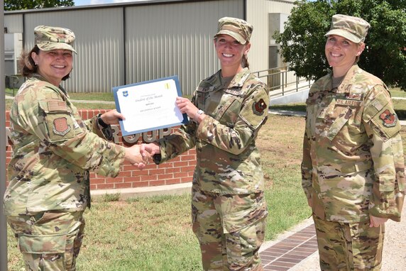 U.S. Air Force Col. Angelina Maguinness, 17th Training Group commander, and Chief Master Sgt. Breana Oliver, 17th TRG superintendent, presents Airman Lindsay Kneep, 315th Training Squadron student, the 17th TRG Student of the Month award for May 2021, on Goodfellow Air Force Base, Texas, June 29, 2021. The 315th Training Squadron trains, educates, and mentors future intelligence, surveillance, and reconnaissance warriors. (U.S. Air Force photo by Senior Airman Jermaine Ayers)