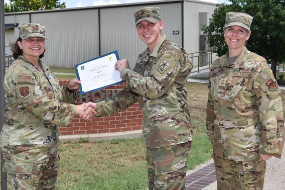 U.S. Air Force Col. Angelina Maguinness, 17th Training Group commander, and Chief Master Sgt. Breana Oliver, 17th TRG superintendent, presents Pfc. Paul Gray, 315th Training Squadron student, the 17th TRG Student of the Month award for May 2021, on Goodfellow Air Force Base, Texas, June 29, 2021. Gray was awarded for his dedication to his squadron and the training he received at Goodfellow. (U.S. Air Force photo by Senior Airman Jermaine Ayers)