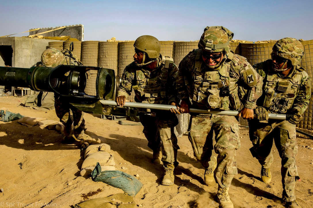 Soldiers train on a military vehicle in a desert.