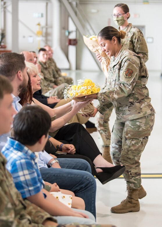 Tech. Sgt. Alicia Williams, a recruiter with the Kentucky Air National Guard, presents a bouquet of roses to the wife of Chief Master Sgt. James Tongate, the incoming state command chief, at his assumption-of-responsibility ceremony at the Kentucky Air National Guard Base in Louisville, Ky., May 15, 2021. (U.S. Air National Guard photo by Senior Airman Chloe Ochs)