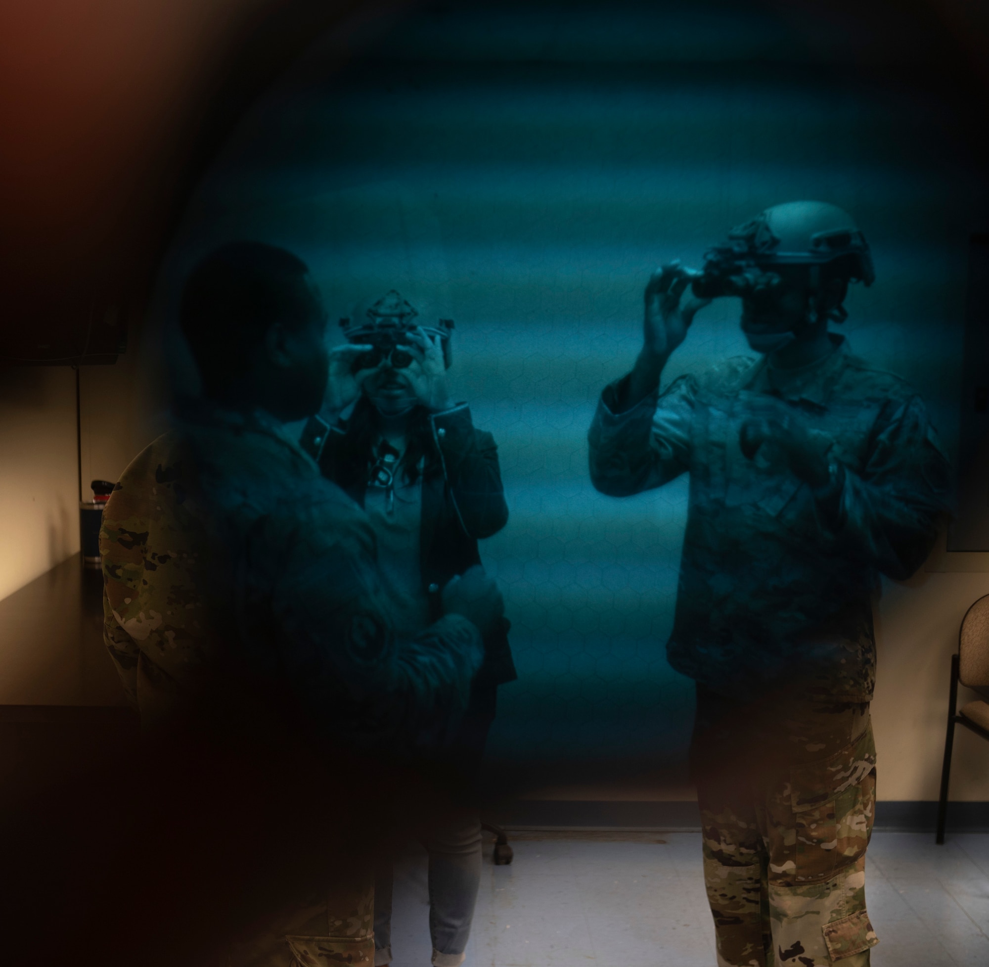 U.S. Air Force Master Sgt. Taurean Dougal, left, teaches U.S. Air Force Col. Travis Edwards, right, 621st Contingency Response Wing commander, and his wife, Michon, center, how to use night vision goggles during an East Coast immersion June 25, 2021, at Joint Base McGuire-Dix-Lakehurst, New Jersey. Edwards and his wife received briefings throughout the day on the various mission sets contained within the CRW. (U.S. Air Force photo by Tech. Sgt. Luther Mitchell)