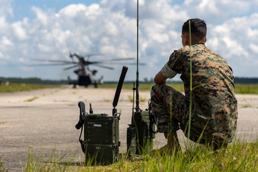 U.S. Marine Corps Lance Cpl. Elvis Agosto-Santiago, a native of Guayanilla, Puerto Rico, and a transmissions system operator with 2d Landing Support Battalion (LSB), 2d Marine Logistics Group, exchanges radio transmissions during a training event on Camp Lejeune, N.C., June 16, 2021. 2d LSB led a training event for Marines with 2d Battalion, 8th Marine Regiment, 2d Marine Division, to observe and gain further knowledge on aerial delivery logistics and operations. (U.S. Marine Corps photo by Lance Cpl. Jacqueline Parsons)