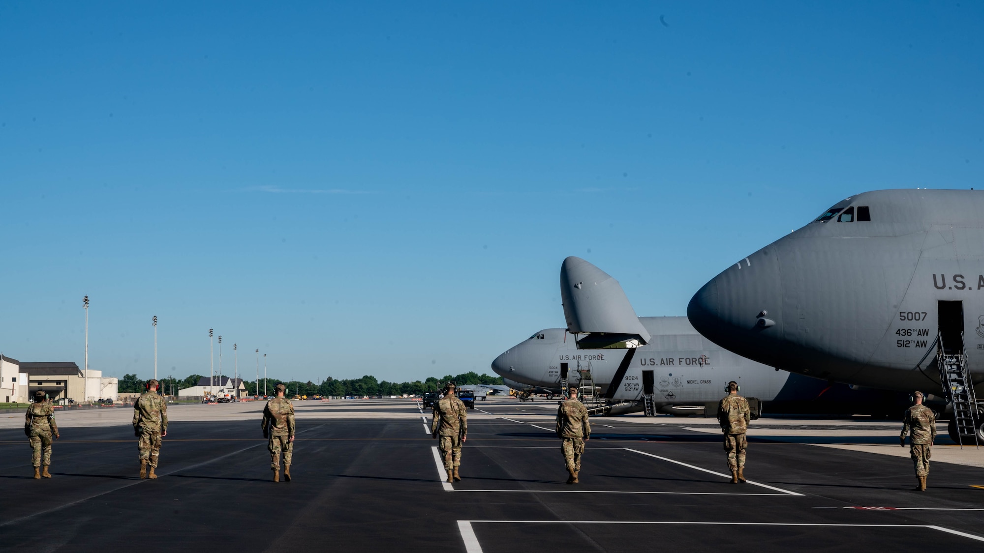 Airmen from the 436th Aircraft Maintenance Squadron  perform a foreign object debris walk on the flight line at Dover Air Force Base, Delaware, June 23, 2021. FOD walks are routinely held to clear the flight line of any objects in the area that could potentially cause damage to aircraft. (U.S. Air Force photo by Senior Airman Faith Schaefer)