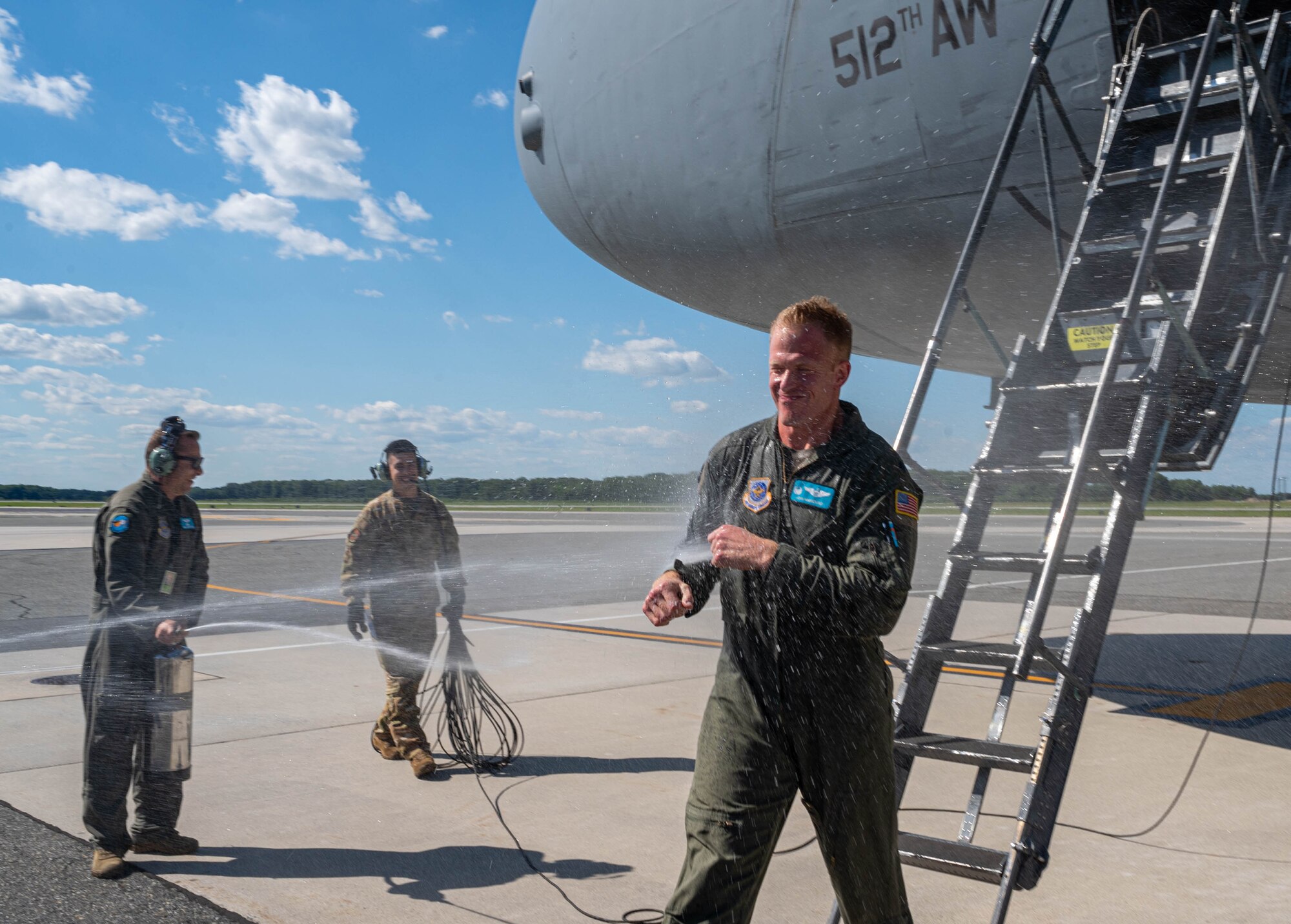 Lt. Col. John Habbestad, 9th Airlift Squadron commander, is sprayed with water to celebrate his final C-5M Super Galaxy flight as the 9th AS commander at Dover Air Force Base, Delaware, June 23, 2021. Habbestad served as commander for two years before. (U.S. Air Force photo by Senior Airman Faith Schaefer)