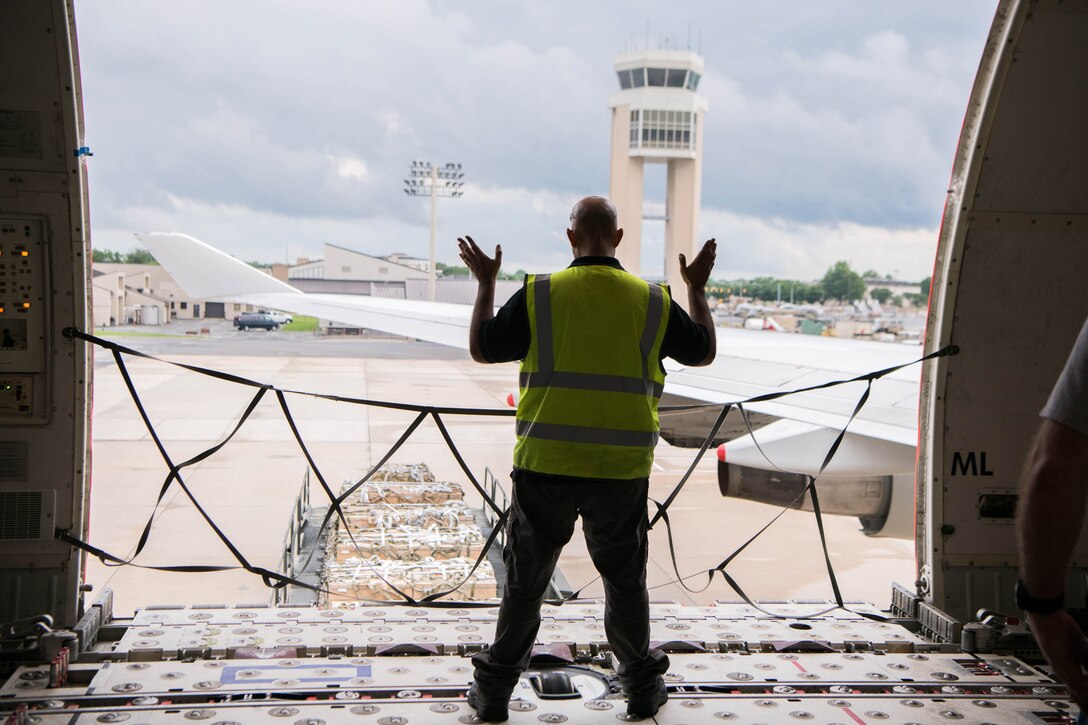 Angel Reyes, National Airlines loadmaster, marshals a K-loader loaded with pallets of materiel bound for Tajikistan onto an aircraft at Dover Air Force Base, Delaware, June 22, 2021. Security cooperation between the U.S. and Tajikistan advances shared security interests and supports regional stability in Central Asia. (U.S. Air Force photo by Mauricio Campino)