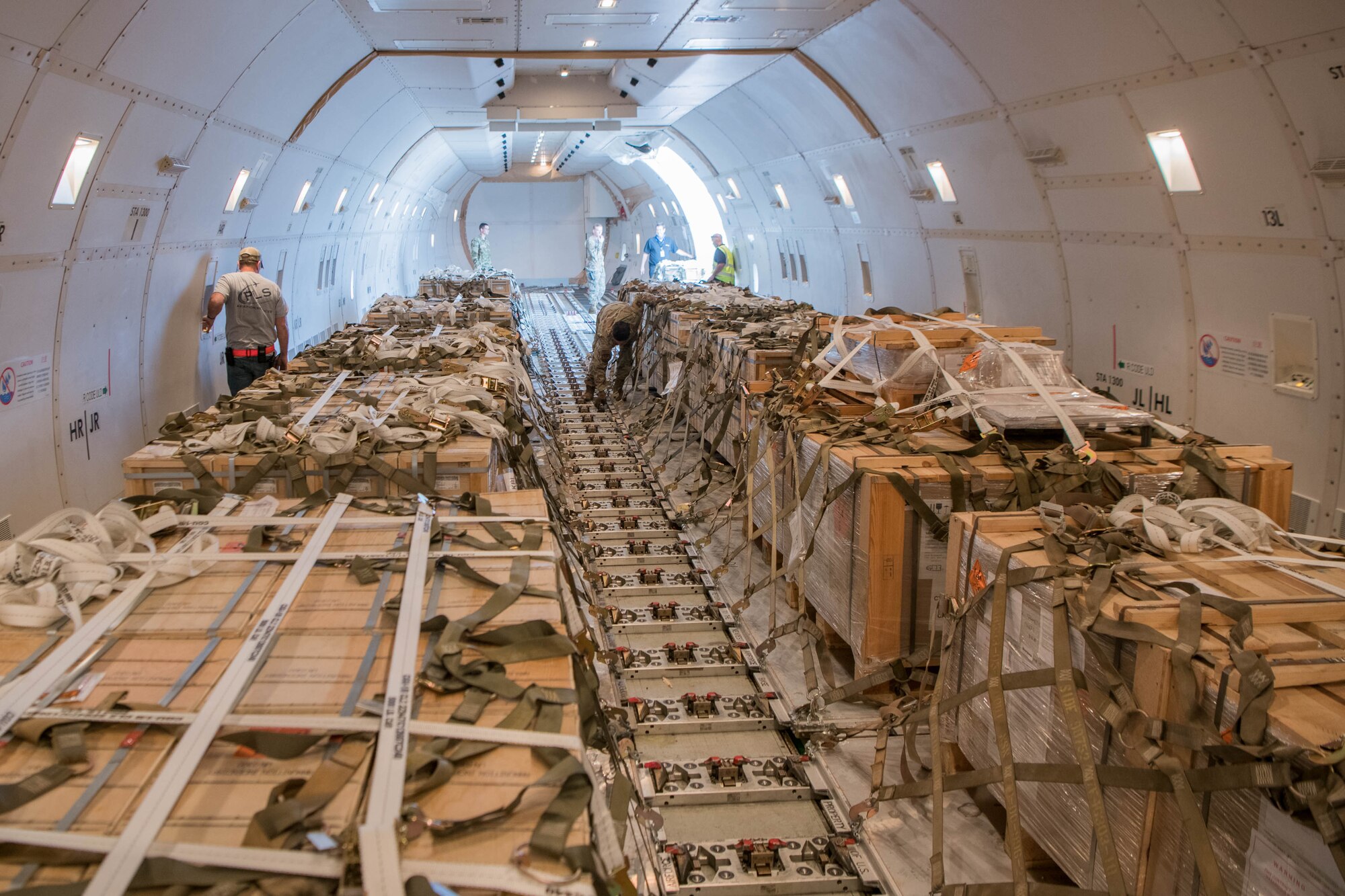 Ramp services personnel from the 436th Aerial Port Squadron, as well as National Airlines loadmasters, check the security of pallets onboard an aircraft bound for Tajikistan at Dover Air Force Base, Delaware, June 22, 2021. Security cooperation between the U.S. and Tajikistan advances shared security interests and supports regional stability in Central Asia. (U.S. Air Force photo by Mauricio Campino)