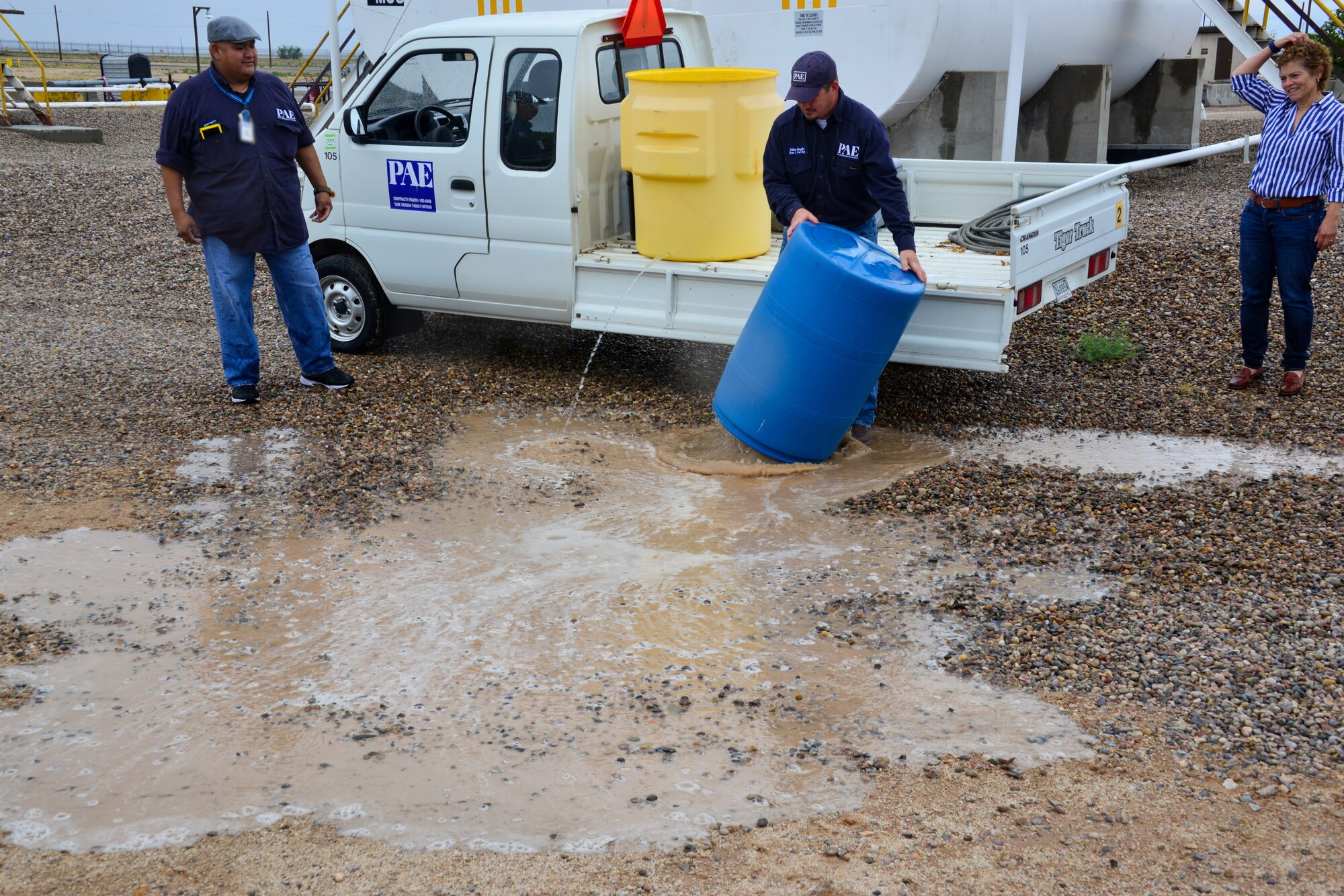 Man demonstrates what a 55 gallon spill looks like to a small group of people at Kirtland, AFB.