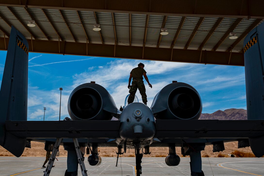 An airman stands on top of an Air Force aircraft.