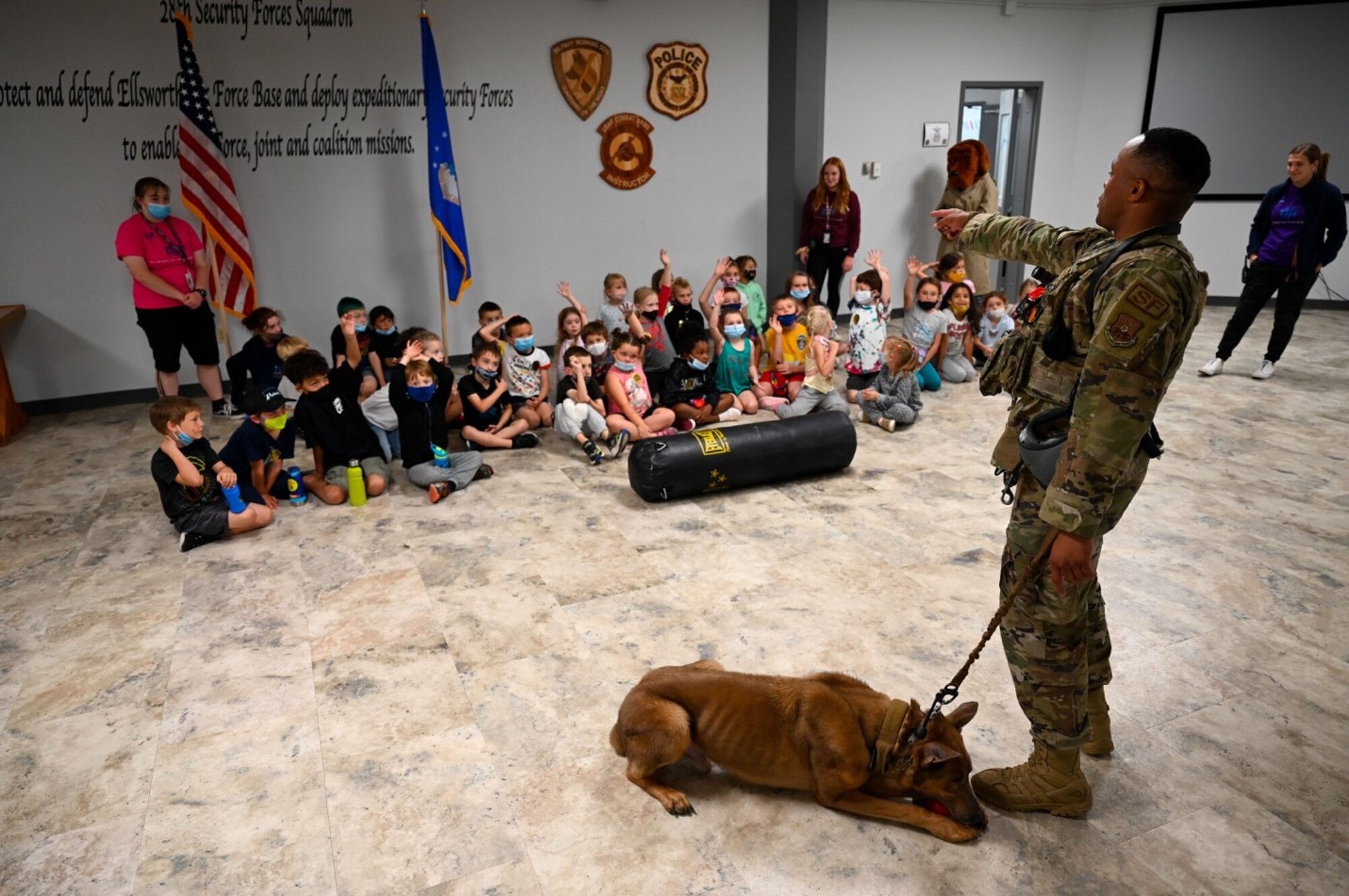 Staff Sgt. Ronald Dyer, a 28th Security Forces Squadron military working dog handler, answers questions about his partner, Lezer, from students of the Ellsworth School Age Care program during a field trip at Ellsworth Air Force Base, S.D., June 25, 2021.