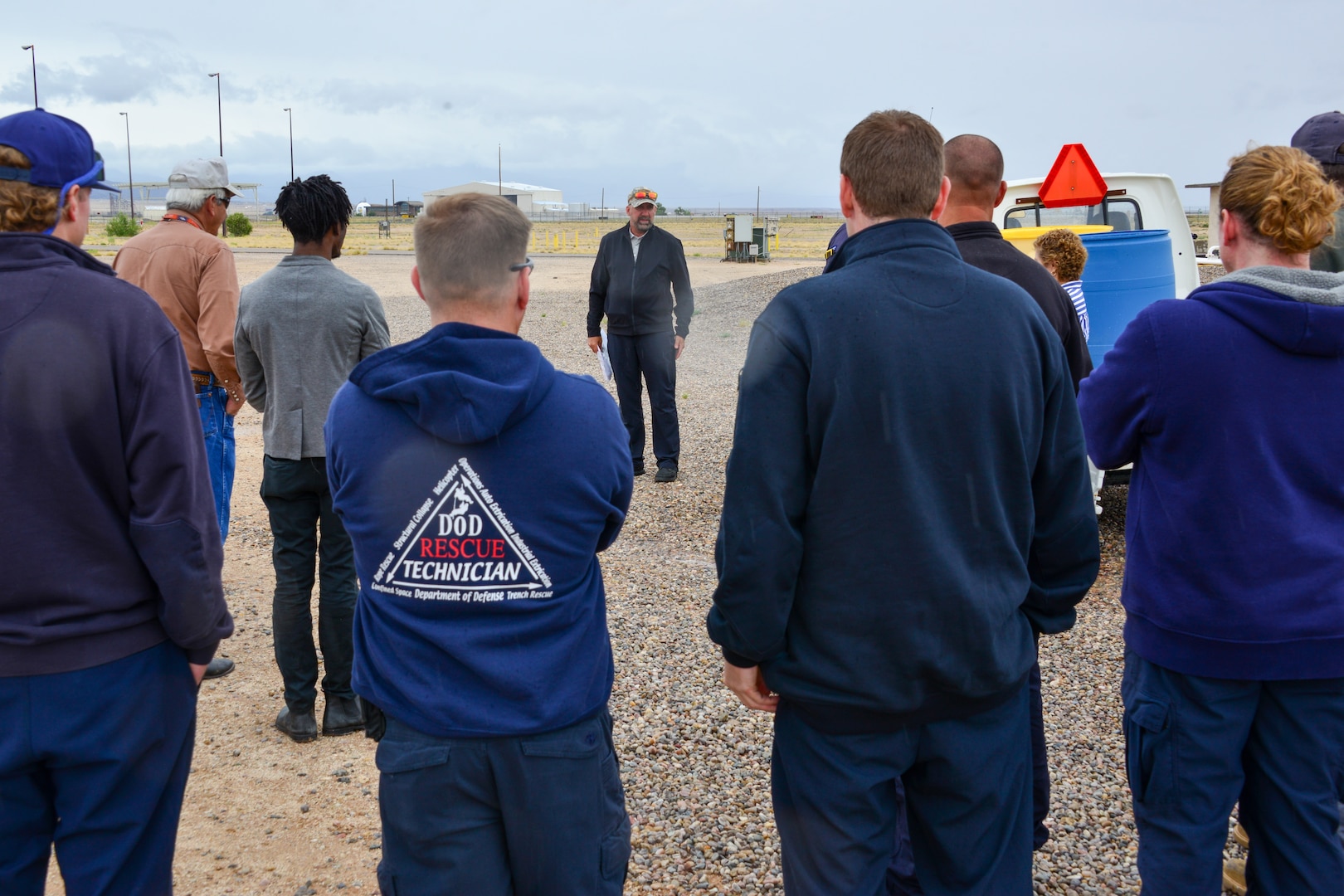 Man demonstrates and explains what a 55 gallon spill looks like to a small group of people at Kirtland, AFB.