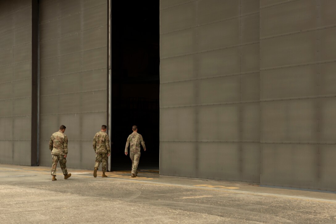 A photo of base leadership walking into an aircraft hangar.