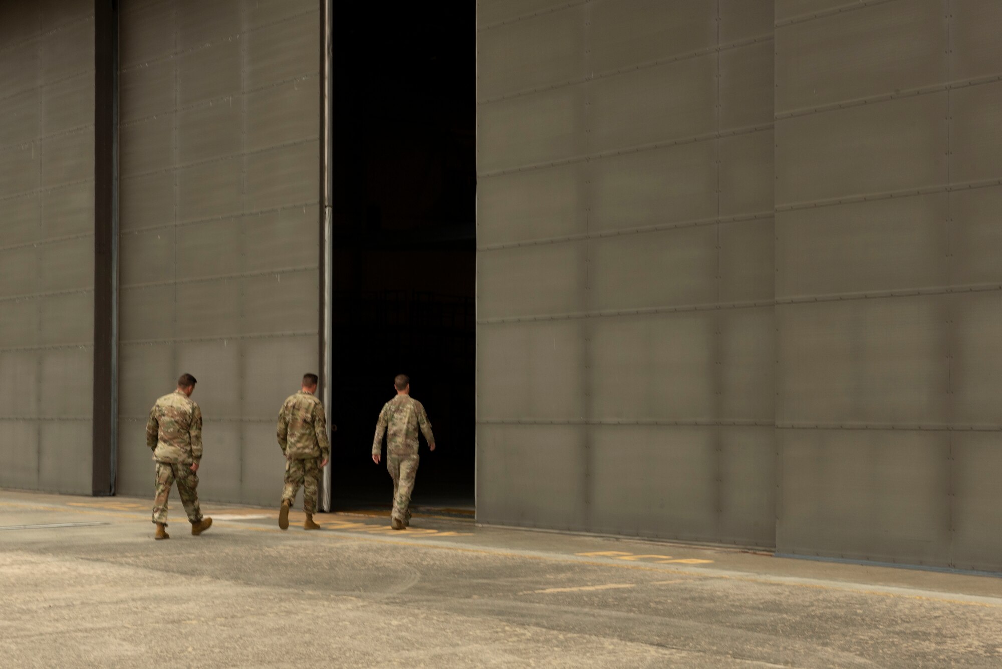 A photo of base leadership walking into an aircraft hangar.