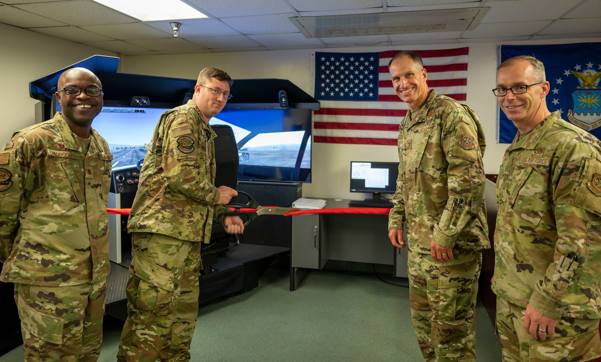 From left, Maj. George Okorodudu, 436th Logistics Readiness Squadron commander, Staff Sgt. Cory Nelson, 436th LRS documented cargo noncommissioned officer in charge, Col. Matt Husemann, 436th Airlift Wing commander, and Chief Master Sgt. Timothy Bayes, 436th AW command chief, cut a ribbon during the opening ceremony for the 550Truckplus driving simulator at Dover Air Force Base, Delaware, June 22, 2021. The simulator immerses drivers in various weather conditions, vehicles, road conditions and equipment malfunctions to produce a safe, well-rounded training environment. (U.S. Air Force photo by Airman 1st Class Cydney Lee)