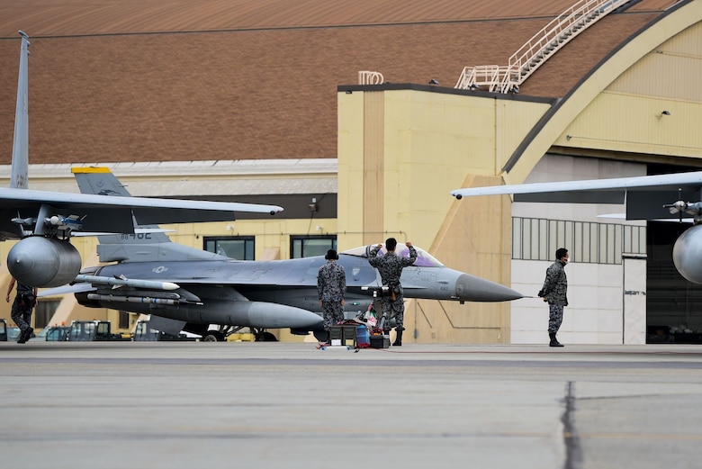 An aircraft maintenance crew member with the Koku Jietai (Japan Air Self Defense Force) strikes the 80th Fighter Squadron “crush em” pose as an F-16 Fighting Falcon assigned to Kunsan Air Base, Republic of Korea, taxis by  during Red Flag-Alaska 21-2 at Eielson Air Force Base, Alaska, June 18, 2021. RF-A is a U.S. Pacific Air Forces-sponsored exercise designed to provide training to U.S. and allied forces in a simulated combat environment. (U.S. Air Force photo by Senior Airman Suzie Plotnikov)