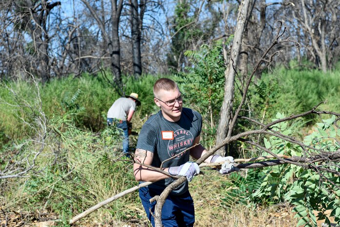 An Airman from Beale Air Force Base works to clear branches and brush, June 25, 2021, in Paradise, California.