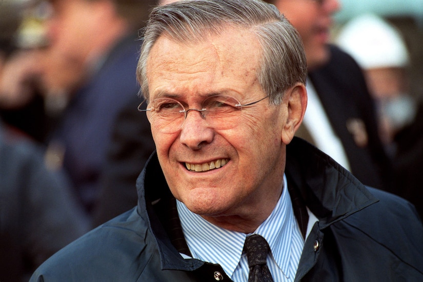Defense Secretary Donald H. Rumsfeld smiles while standing in a crowd.