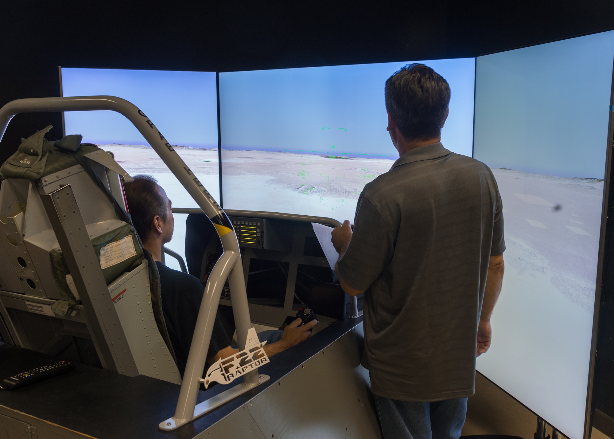 A family member tries out an F-22 Raptor flight simulator during the 412th Electronic Warfare Group Family Day at Edwards Air Force Base, California, June 18. (Air Force photo by Kyle Brasier)