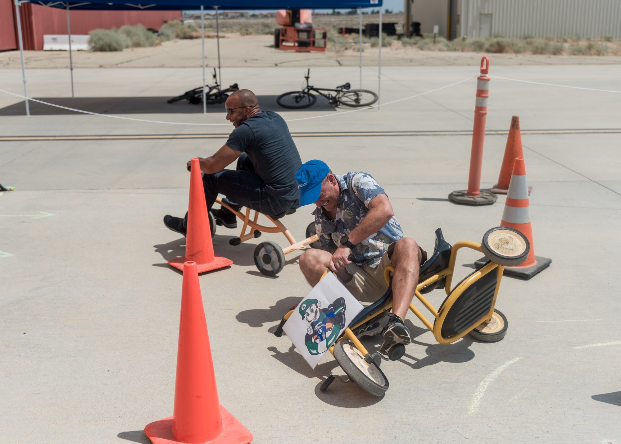 Col. Jay Orson, 412th Electronic Warfare Group commander, wipes out as Col. Randel Gordon, 412th Test Wing vice commander, goes for the win during a tricycle obstacle course race at the 412th EWG Family Day at Edwards Air Force Base, June 18. (Air Force photo by Bryce Bennett)