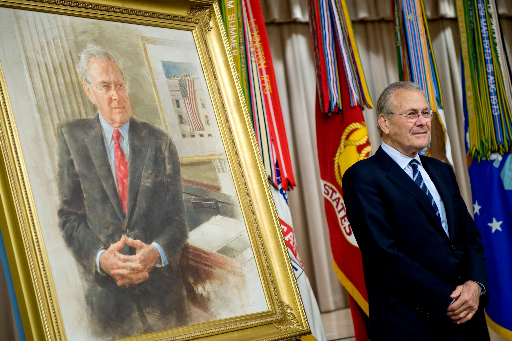 Former Defense Secretary Donald H. Rumsfeld stands next to a portrait of himself.