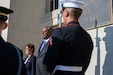 A man and a woman flanked by uniformed service members stand at the entrance of the Pentagon.