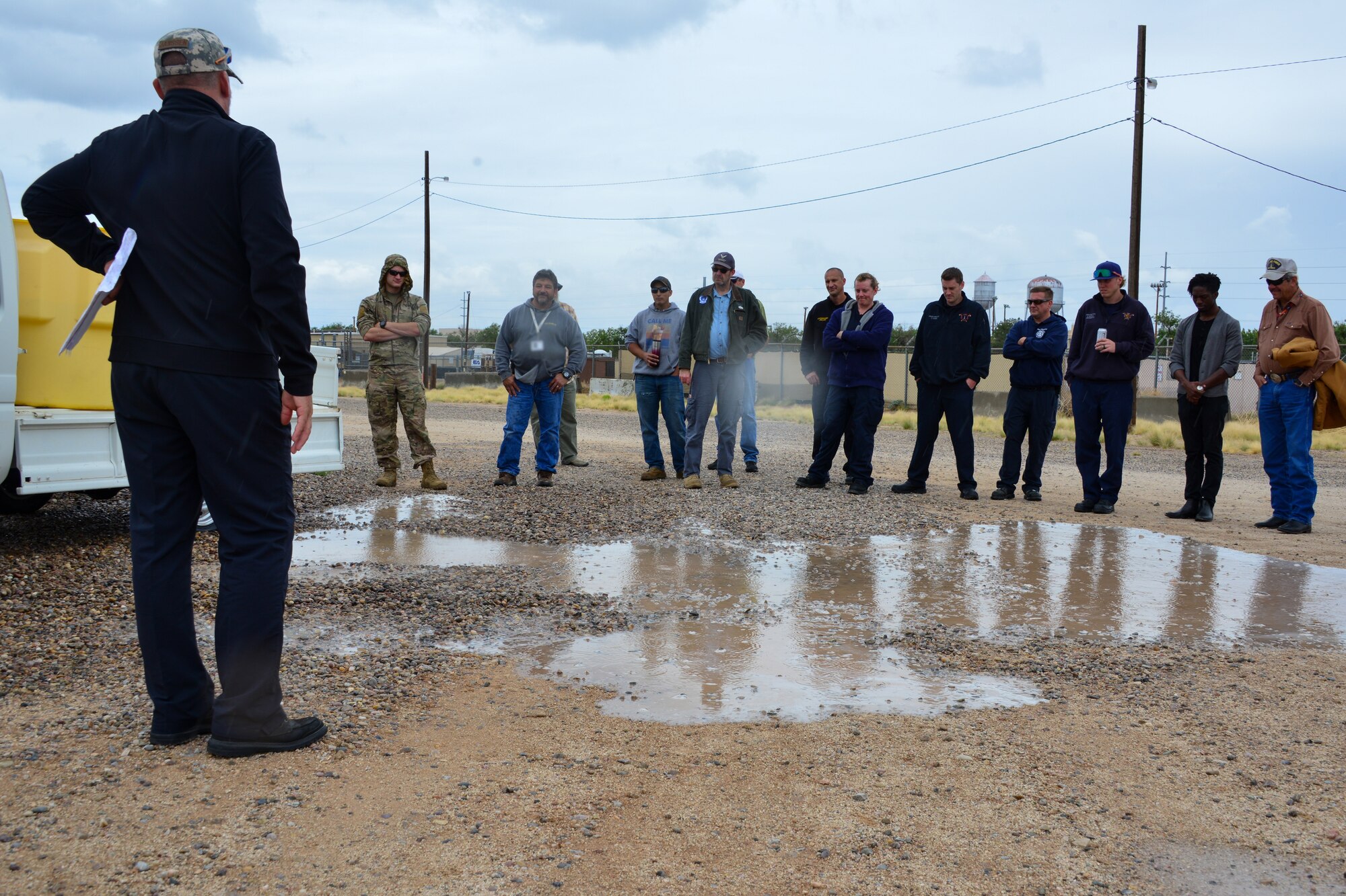 Man demonstrates what a 55 gallon spill looks like to a small group of people at Kirtland, AFB.