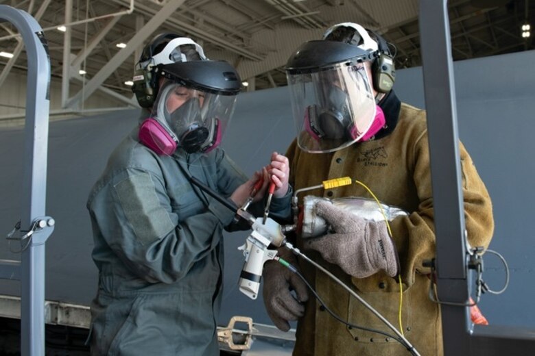 Staff Sgt. Chynna Patterson, a 28th Maintenance Group additive manufacturing spray technician, and David Darling, the 28th MXG additive manufacturing site manager, wait for the VRC Raptor Cold Spray machine to heat up at Ellsworth Air Force Base, S.D., May 12, 2021.